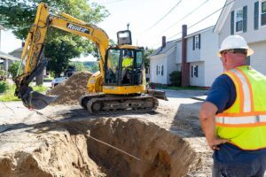 A waterworks crew using the Team NCT service line puller kit and a backhoe to install new service lines with minimal trench digging in a residential area