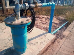 A dewatering system including a pump and blue piping sits on a concrete pad outside.